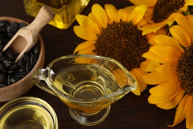 Photo of Sunflowers, oil and seeds on wooden table, closeup