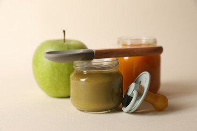 Photo of Healthy baby food, apple, pacifier and spoon on beige background