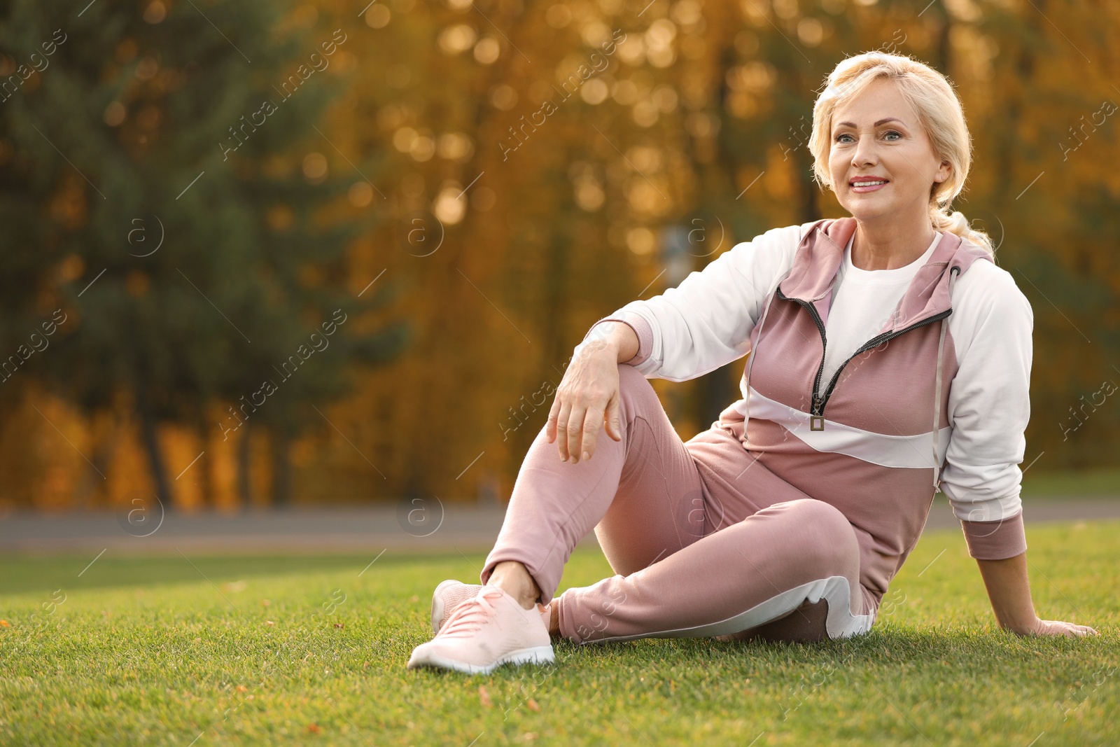 Photo of Happy mature woman sitting on grass in park