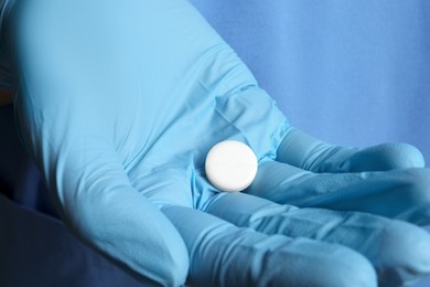 Photo of Doctor in medical glove holding pill, closeup view
