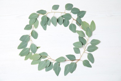 Flat lay composition with fresh eucalyptus leaves and space for design on white wooden background