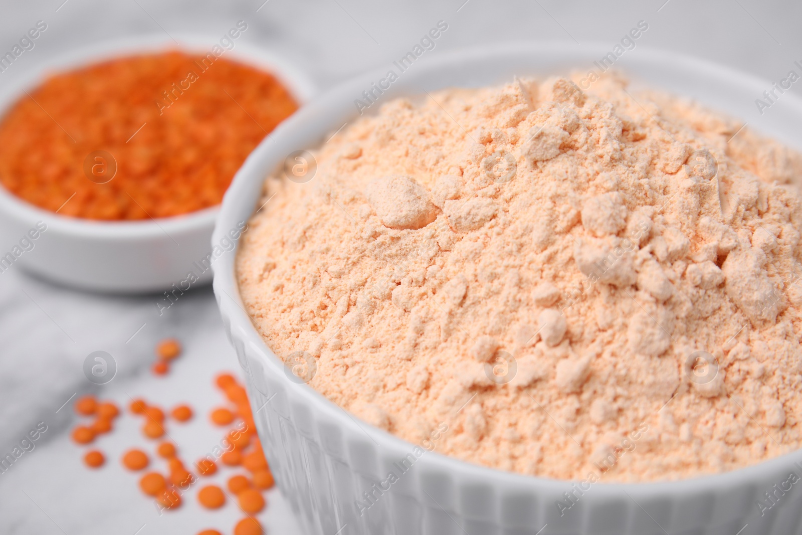 Photo of Lentil flour and seeds on white marble table, closeup