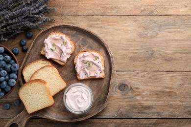 Photo of Tasty sandwiches with cream cheese, thyme and blueberries on wooden table, flat lay. Space for text