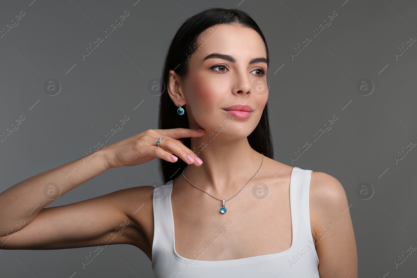 Photo of Beautiful young woman with elegant jewelry on dark grey background