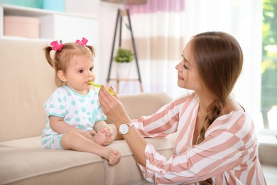 Photo of Caring mother feeding her cute little baby with healthy food at home