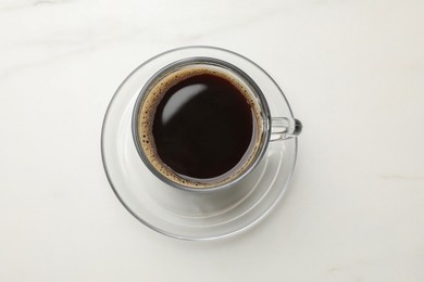 Cup of aromatic coffee on white table, top view