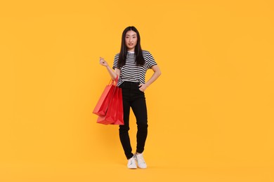 Photo of Beautiful woman with shopping bags on yellow background