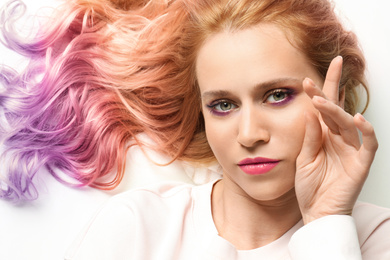 Image of Portrait of young woman with dyed long curly hair on white background