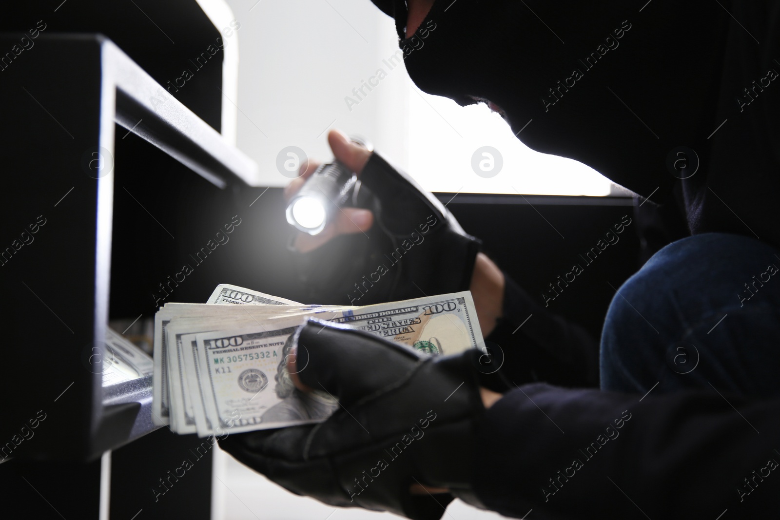 Photo of Thief taking money out of steel safe indoors, closeup