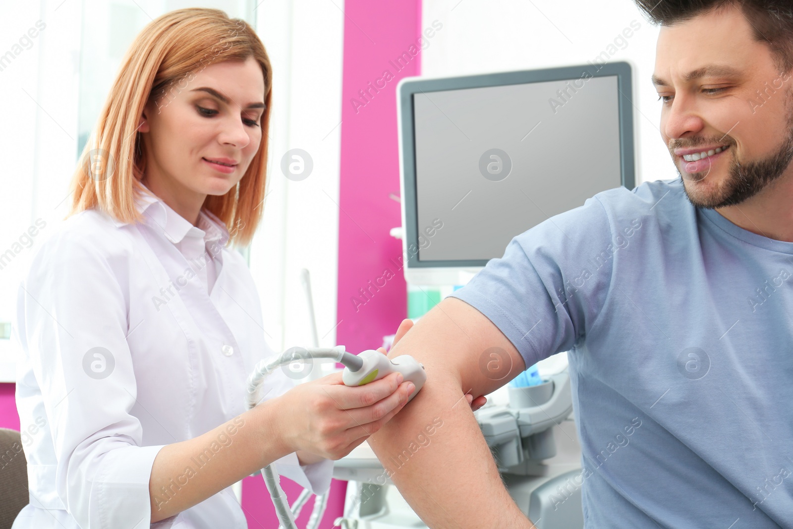 Photo of Doctor conducting ultrasound examination of elbow joint in clinic