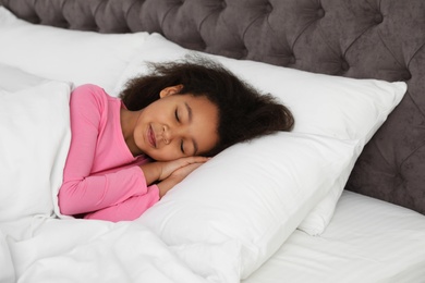 Photo of Cute little African-American girl sleeping in bed