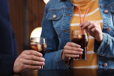 Photo of People holding glasses of cola with ice on blurred background, closeup
