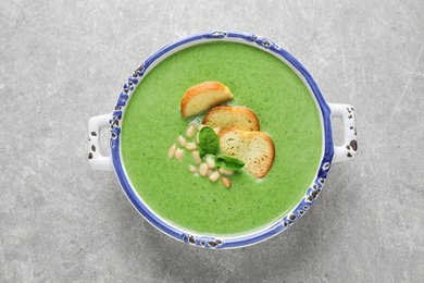 Photo of Bowl of healthy green soup with fresh spinach on light table, top view