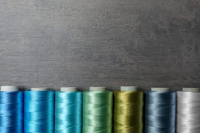 Photo of Color sewing threads on gray background, top view