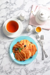 Photo of Tasty pancakes with syrup and cup of tea on table, top view
