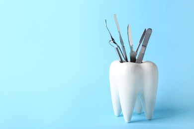 Photo of Tooth shaped holder with professional tools on color background. Space for text