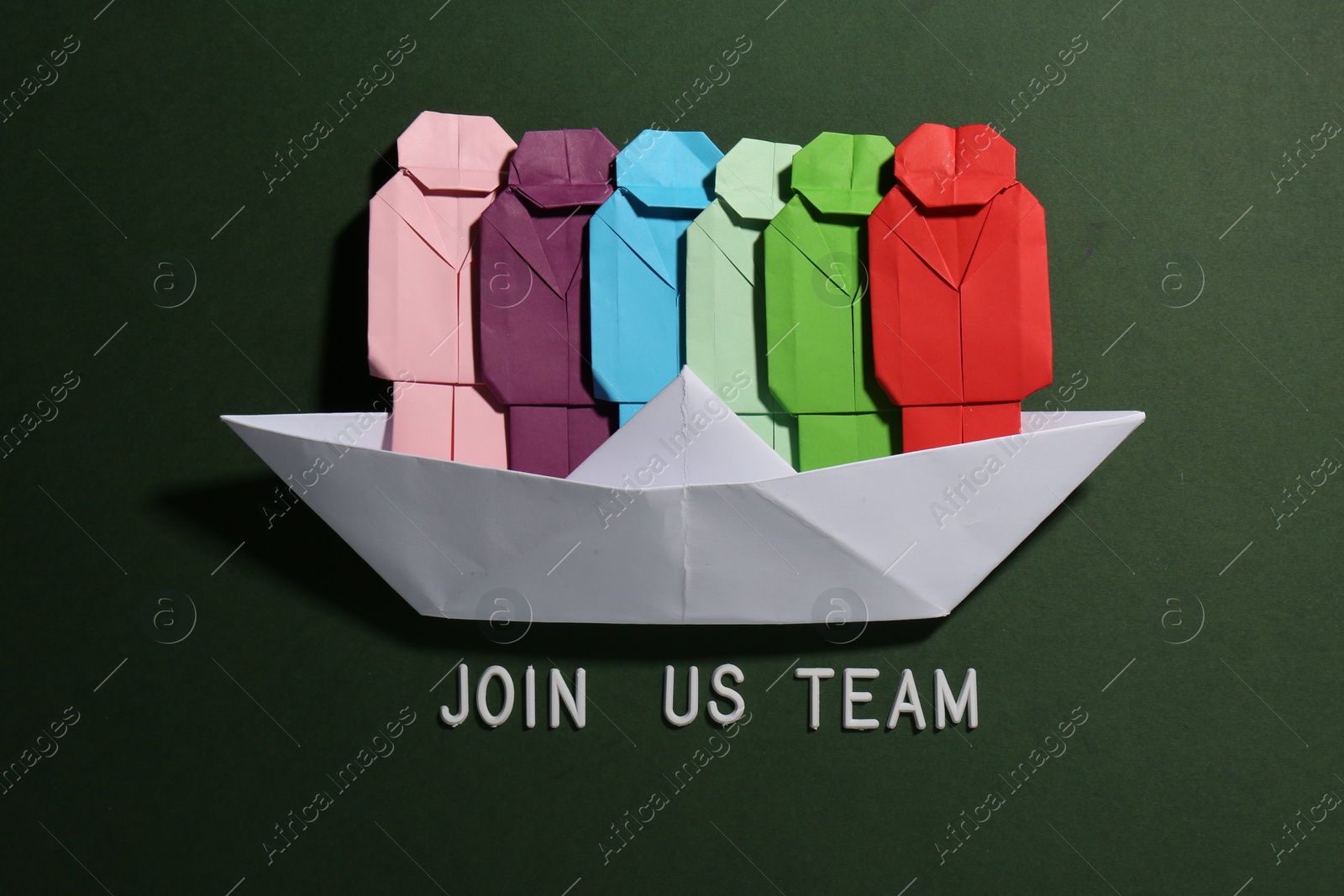 Photo of Many colorful paper figures in boat and phrase Join Us Team on green background, flat lay. Recruiter searching employee