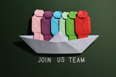 Photo of Many colorful paper figures in boat and phrase Join Us Team on green background, flat lay. Recruiter searching employee