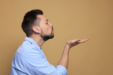 Photo of Handsome man blowing kiss on beige background. Space for text