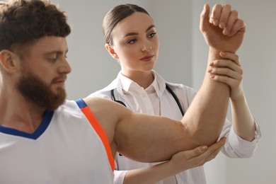 Photo of Sports injury. Doctor examining patient's hand in hospital