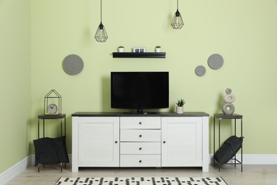 Photo of Modern TV set near green wall in living room