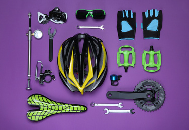 Photo of Set of different bicycle tools, accessories and parts on purple background, flat lay