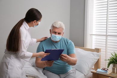 Photo of Doctor working with senior man in protective mask at nursing home