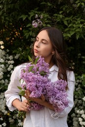 Photo of Attractive young woman with lilac flowers outdoors