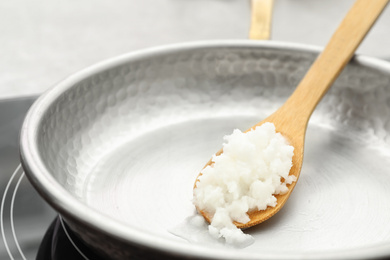 Frying pan with coconut oil on induction stove, closeup. Healthy cooking