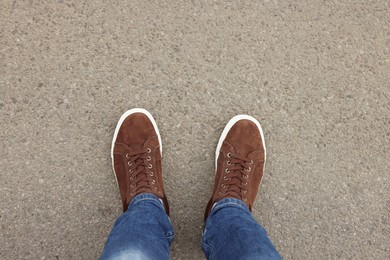 Photo of Man in stylish sneakers standing on asphalt, top view. Space for text