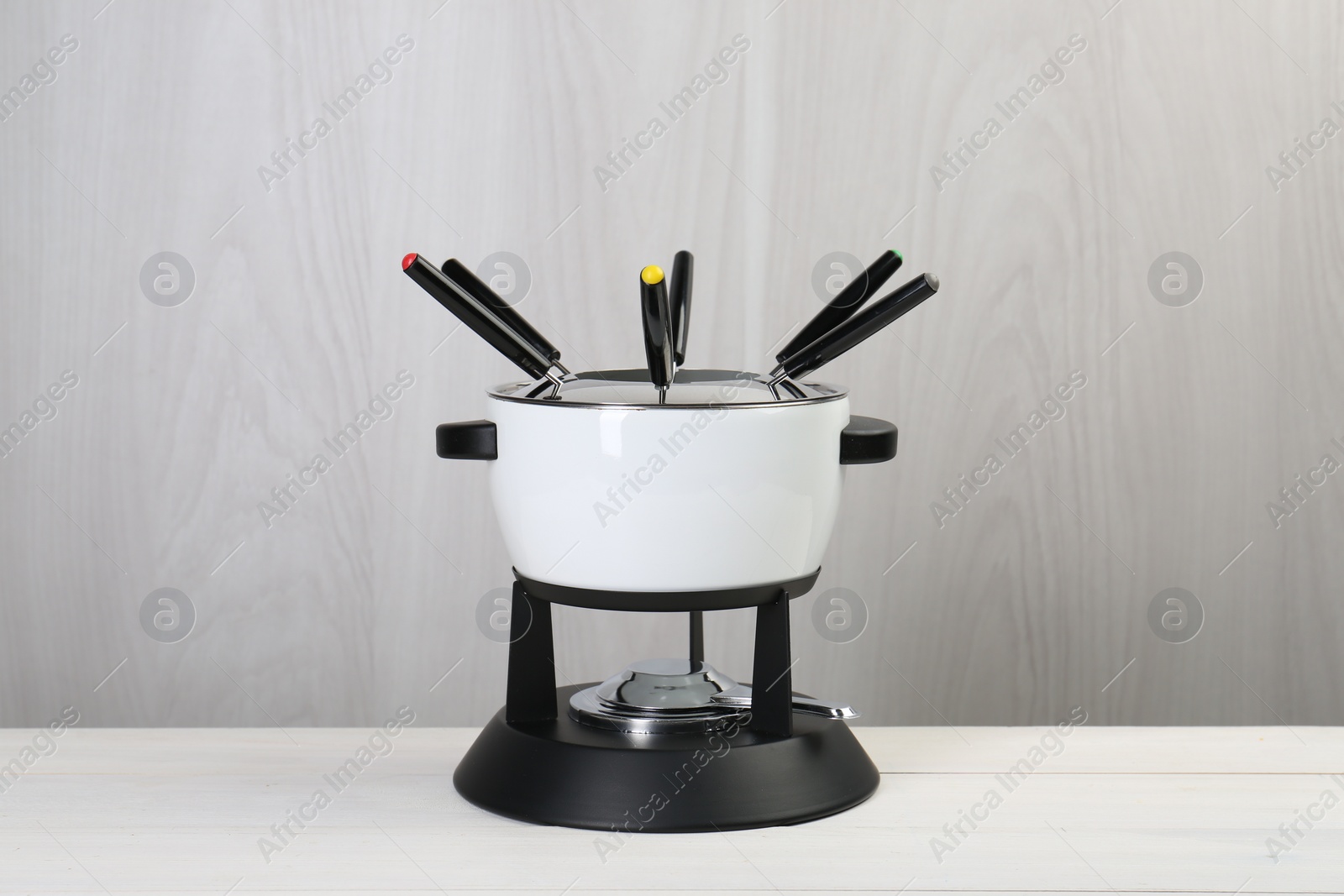 Fondue set on white wooden table. Kitchen equipment Photo of Fondue set on white wooden table. Kitchen equipment