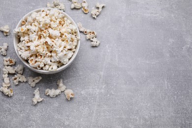 Photo of Bowl of tasty popcorn on grey table, flat lay. Space for text