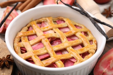 Photo of Baking dish with tasty apple pie and spices on table, closeup