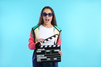 Photo of Emotional woman with 3D glasses and clapperboard on color background. Cinema show