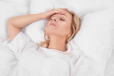 Photo of Woman suffering from headache in bed. Hormonal disorders