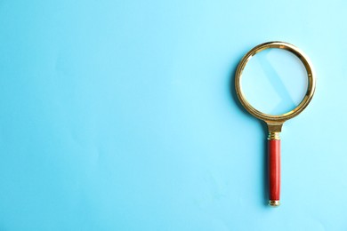 Photo of Top view of magnifier glass on light blue background, space for text. Find keywords concept