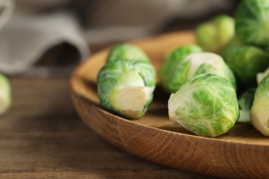 Plate with fresh Brussels sprouts on wooden table, closeup