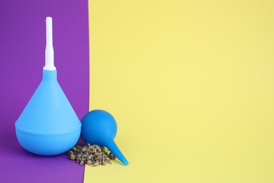 Photo of Enemas and dry chamomile on color background, space for text