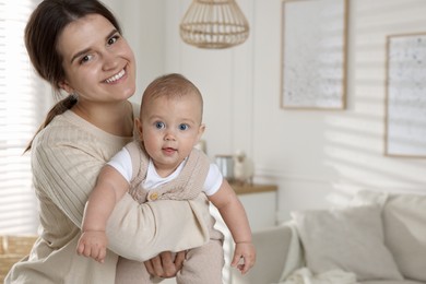 Photo of Happy young mother with her baby in living room. Space for text