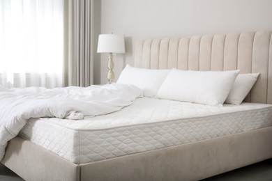 Photo of Comfortable bed with soft white mattress, blanket and pillows indoors
