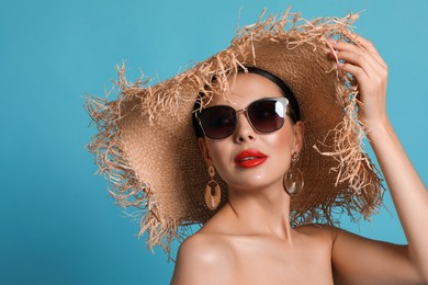 Photo of Attractive woman in fashionable sunglasses and wicker hat against light blue background. Space for text