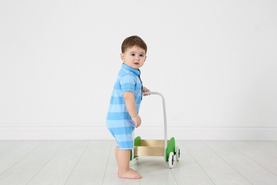 Photo of Cute baby playing with toy walker, indoors