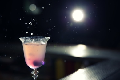 Photo of Glass of cosmopolitan martini cocktail in bar, closeup. Space for text