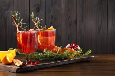 Photo of Christmas Sangria cocktail in glasses, ingredients and fir tree branches on wooden table. Space for text