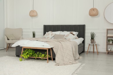 Photo of Stylish bedroom interior with large comfortable bed and armchair