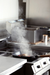 Photo of Cooking delicious meat on frying pan in restaurant kitchen
