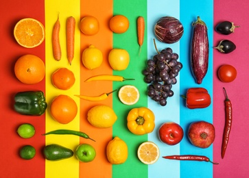 Photo of Rainbow composition with fresh vegetables and fruits on color background, flat lay