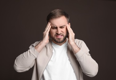 Photo of Young man suffering from headache on dark background