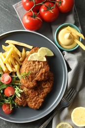 Photo of Tasty schnitzels served with potato fries, tomatoes and arugula on grey table, flat lay
