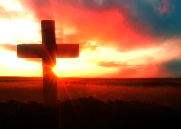Image of Silhouette of Christian cross outdoors at sunset